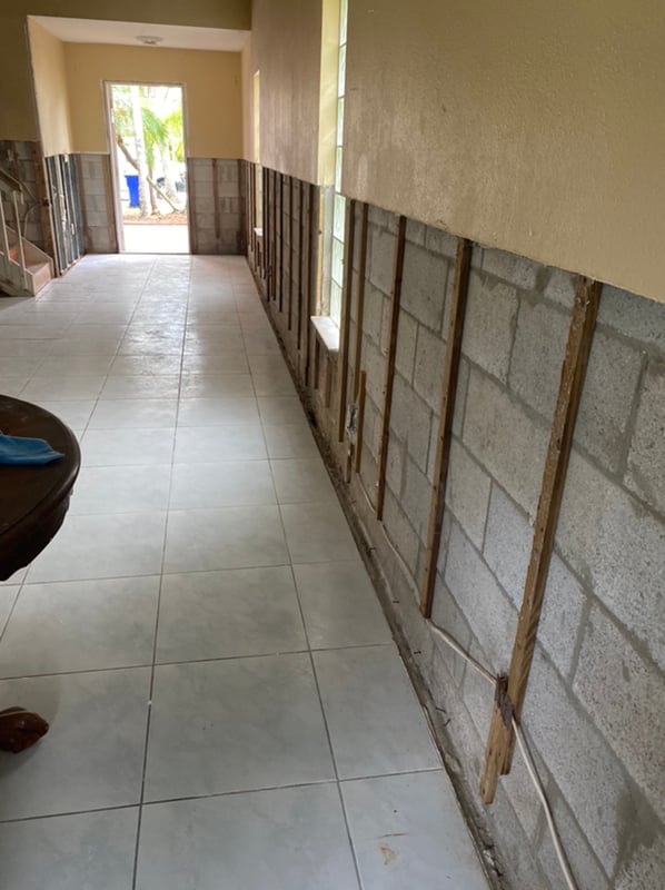 Flood cut and containment in progress on a water-damaged wall