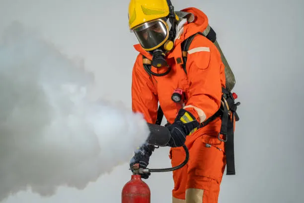 Firefighter in full protective gear extinguishing a fire