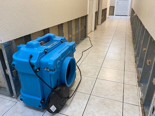 Commercial air movers drying a water-damaged room in a South Florida home