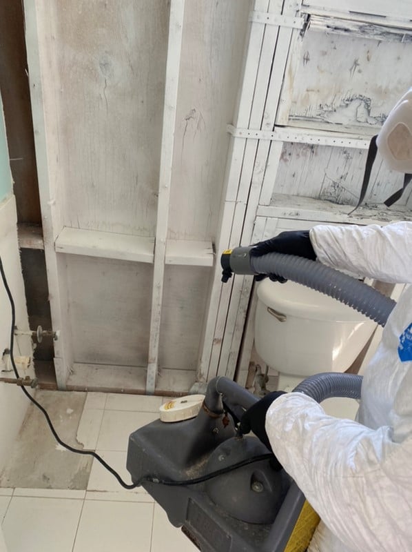 Swift Restoration technician HEPA vacuuming a flood-cut wall cavity